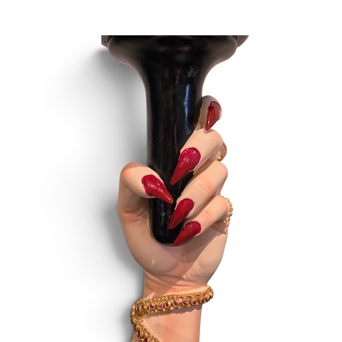 Hand-painted Italian red stiletto nails holding a black candle stand with gold jewelled snake bangle.