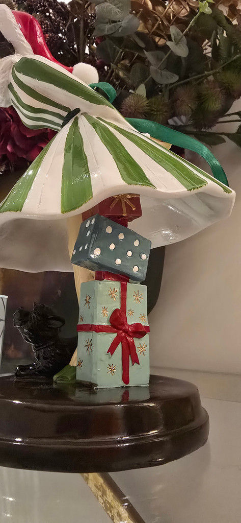 Close-up of the December Diamonds figurine base showing a little black dog and a stack of hand-painted Christmas gifts.