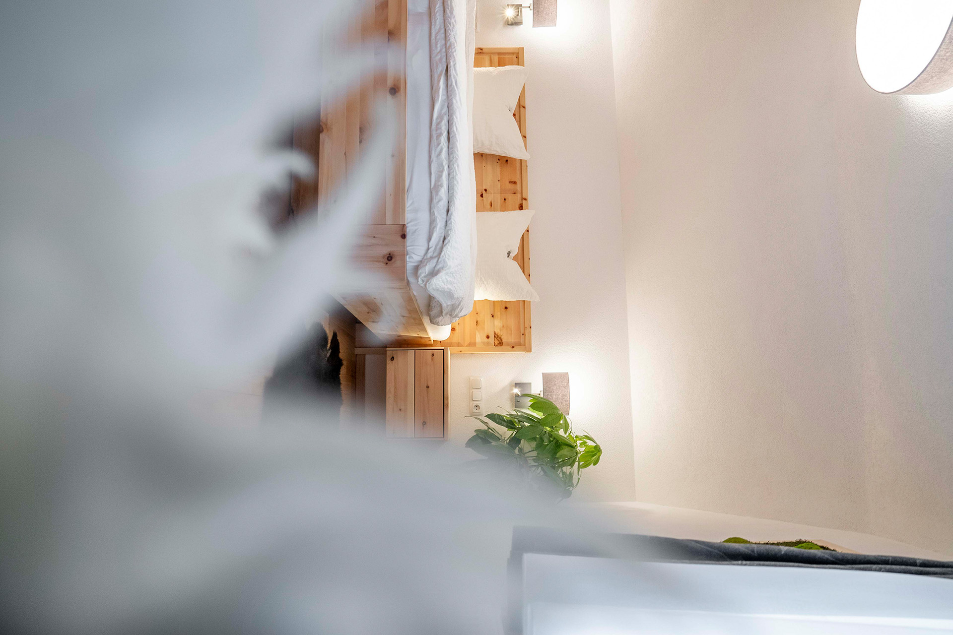 Gemütliches Zimmer im Stoagraue mit Holzbett, weißen Kissen und warmer Tiroler Atmosphäre.