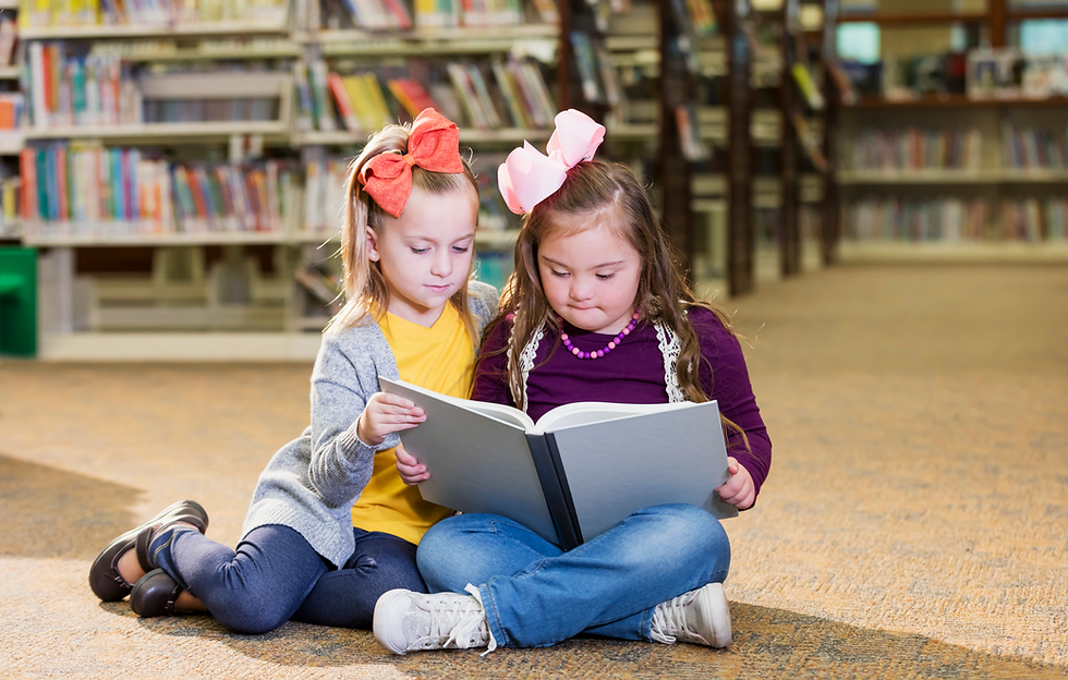 Two young children reading a book in a library.png