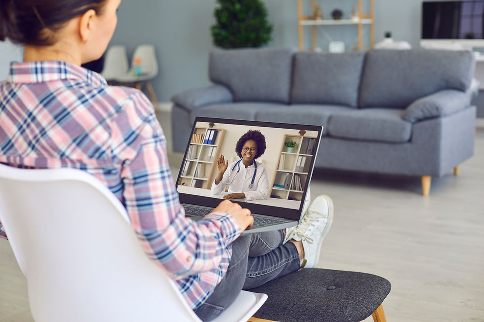 Young woman talking to black female doctor via video call on laptop computer, over shoulde
