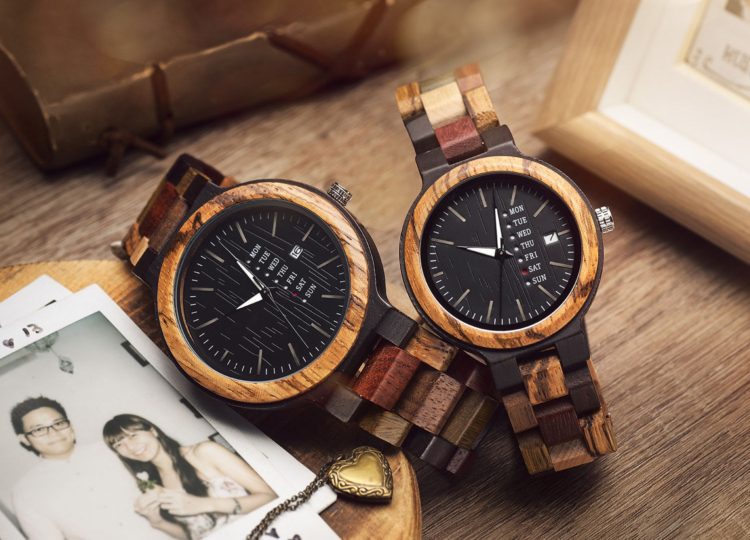 Two wooden couple watches sitting on top of a wooden table with props and photo print.