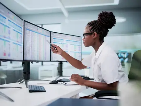 A woman in a white shirt is typing on a computer, concentrating on her task at a desk.
