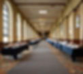 Vendor exhibit tables lined up in hallway at a conference with some books on the tables,