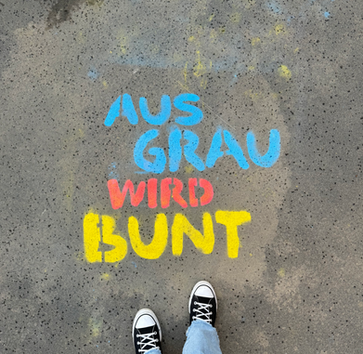 Schriftzug Aus Grau wird bunt auf dem Boden zu lesen