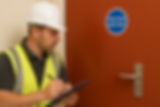 Professional fire door inspector examining fire door components during routine compliance inspection in UK building