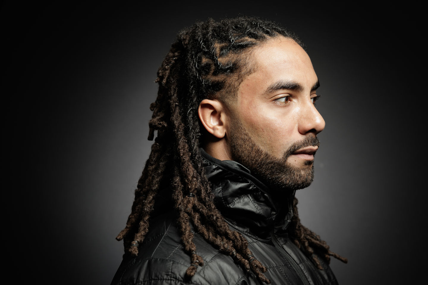 Man with dreadlocks, looking to the right. EDITORIAL PORTRAITS Nick Johnson Photo.