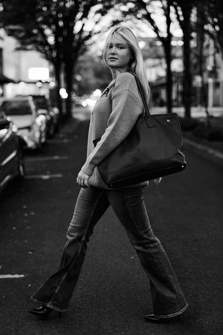Blonde model crossing the street in denim jeans and a Prada Sweater in Downtown Eugene Oregon carrying a fashionable handbag