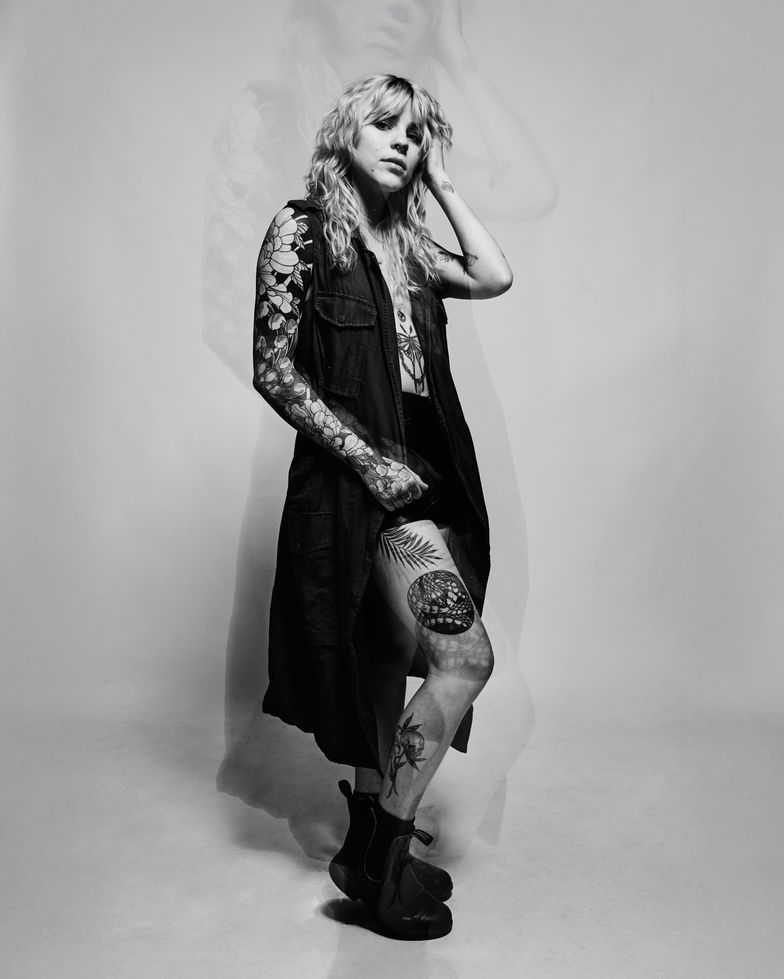 Stylish woman with tattoos, black vest, and boots