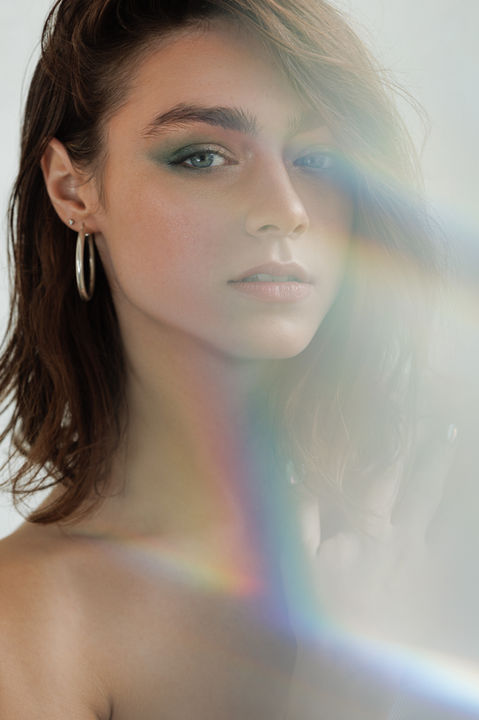 Young woman looking at the camera, BEAUTY, with soft lighting and hoop earrings. Nick Johnson Photo