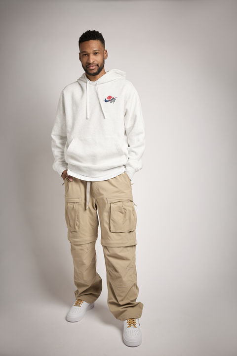 Man in white hoodie and tan cargo pants. Standing in a studio setting. Nick Johnson Photo.