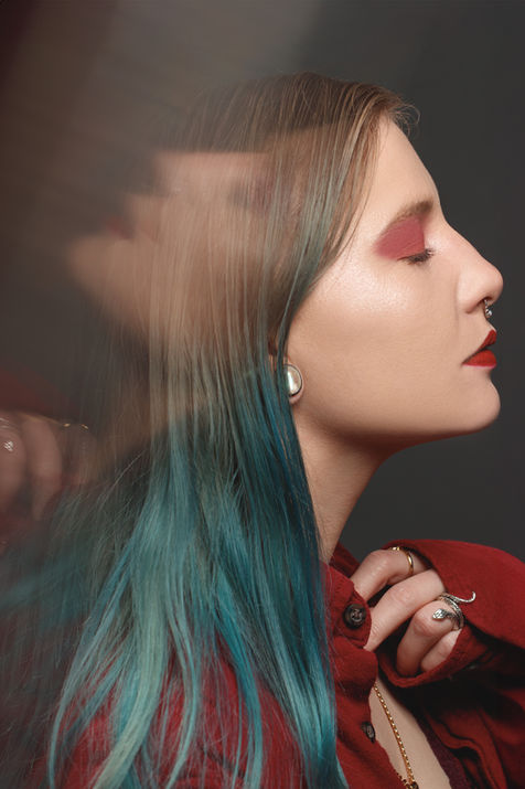 Woman with red lipstick and aqua hair, side profile. Beauty in a studio setting.