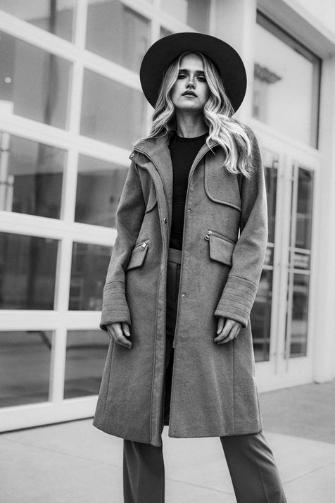 Woman wearing a coat and a hat poses by a glass door FASHION. Nick Johnson Photo