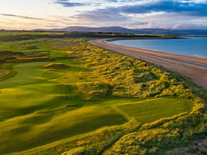 A dramatic aerial view of a seaside golf hole