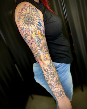 A watercolour sleeve tattoo of roses and sunflowers