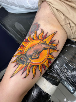 A vibrant colour tattoo of a ram and a sun, done in a Neo Traditional style.