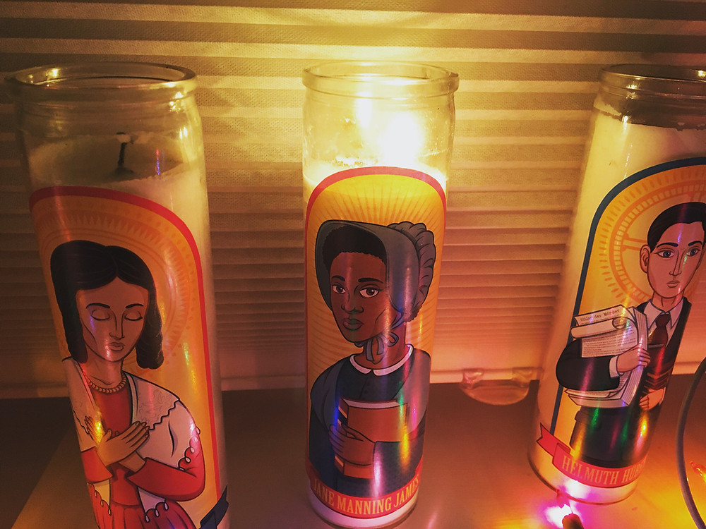 Matt Page's Jane Manning James' prayer candle lit, next to his Emma Smith and Helmuth Hubener candles, with some Christmas lights just outside the frame.