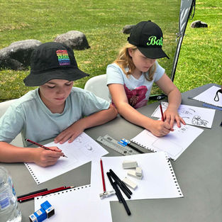 Two children are focussed on drawing at the comic workshop