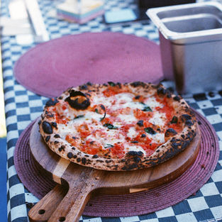 Slaps woodfired pizza have a delicious looking pizza ready for pick up on a big round wooden board
