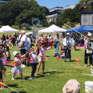 Tinka Bubbles sending giant bubbles into the park to the delight of children watching