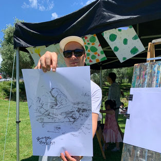 A young man shows his drawing to the camera