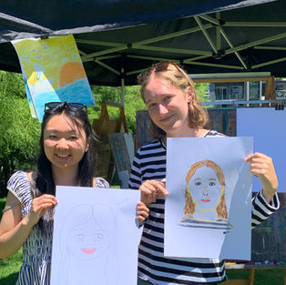 Two young women happily display their drawings