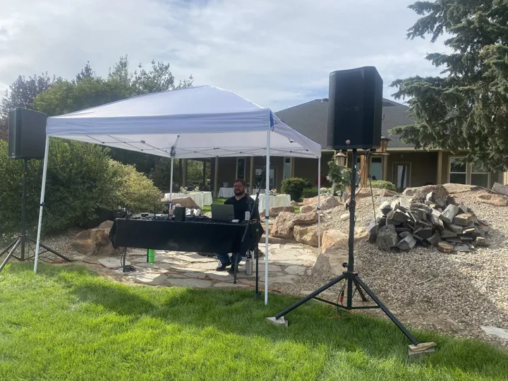 Speakers and a covered DJ setup for an outdoor wedding.