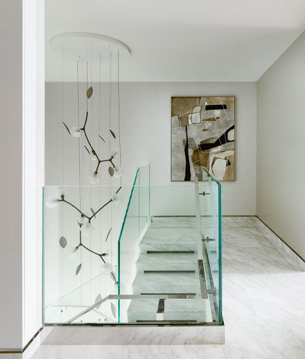 Modern glass staircase with decorative chandelier and abstract art in hallway