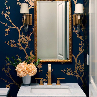 Elegant bathroom with gold accents, mirror, floral wallpaper, and sink. Nu Projects Dubai.