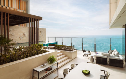 Luxury outdoor patio with sea view, table, chairs, and calm blue ocean.