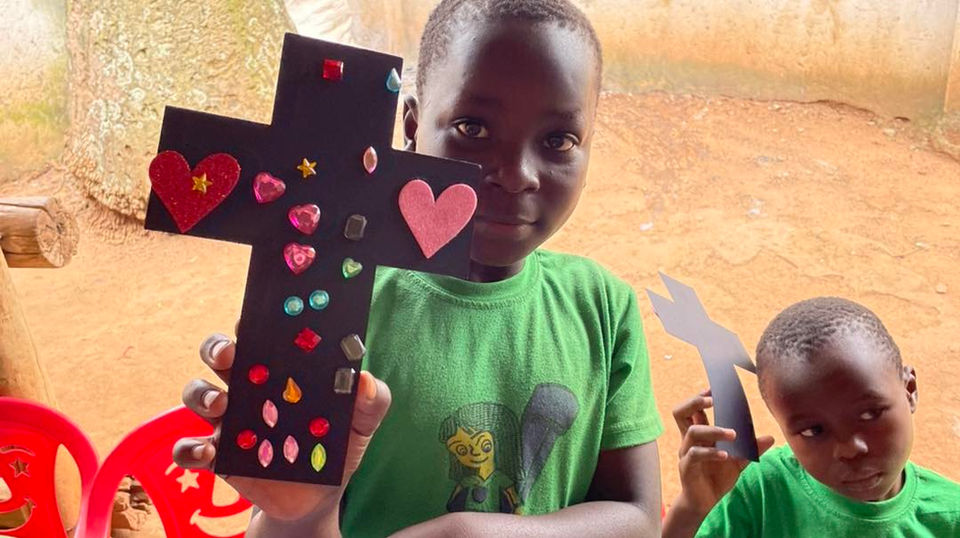 Children pictured holding up their crafts - decorated crosses.