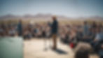 A man speaking to a crowd from a small stage in the mojave desert._edited.jpg