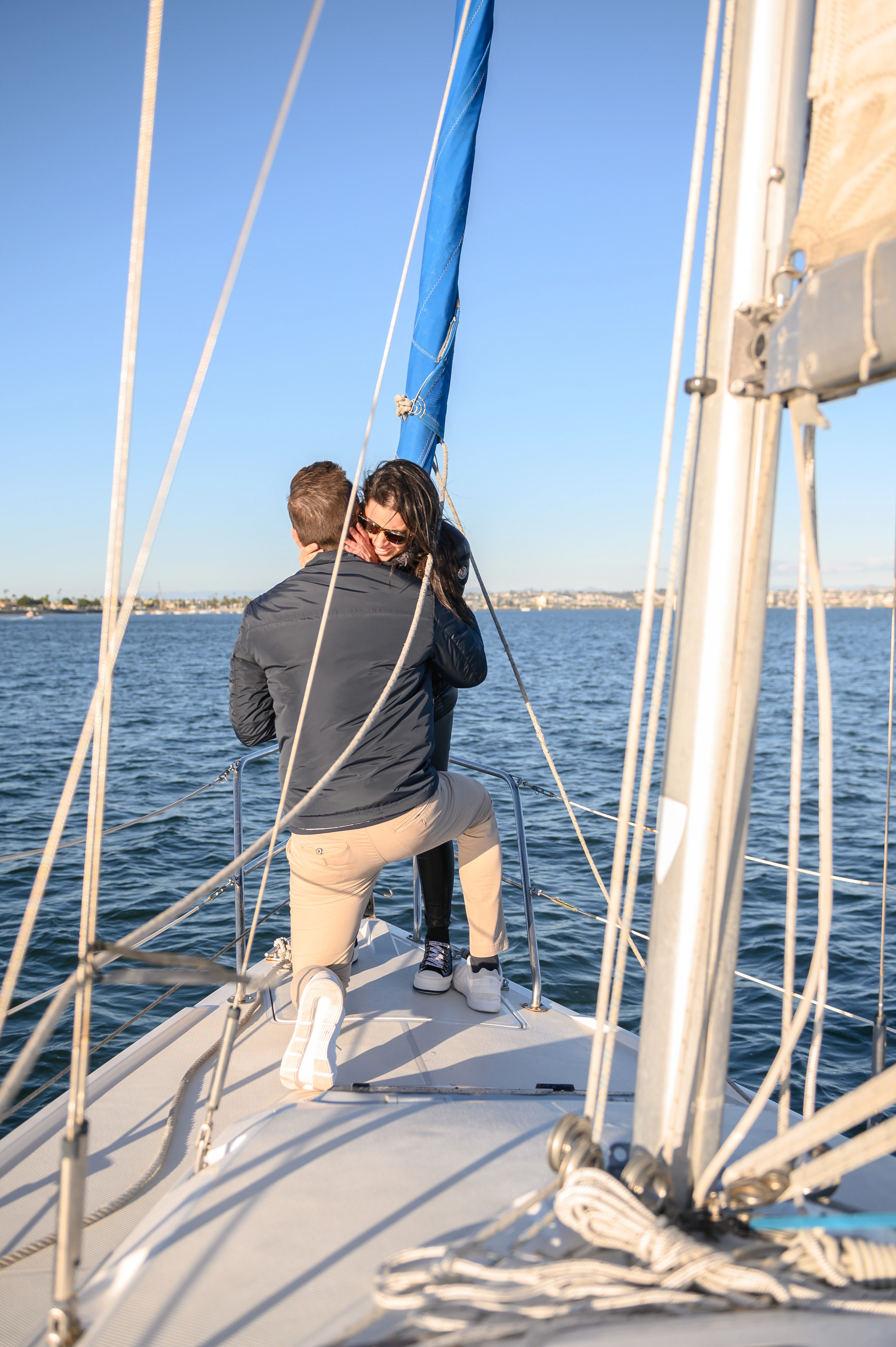 Sailboat proposal in San Diego featuring a couple embracing on the deck, showcasing the beauty of a romantic engagement.