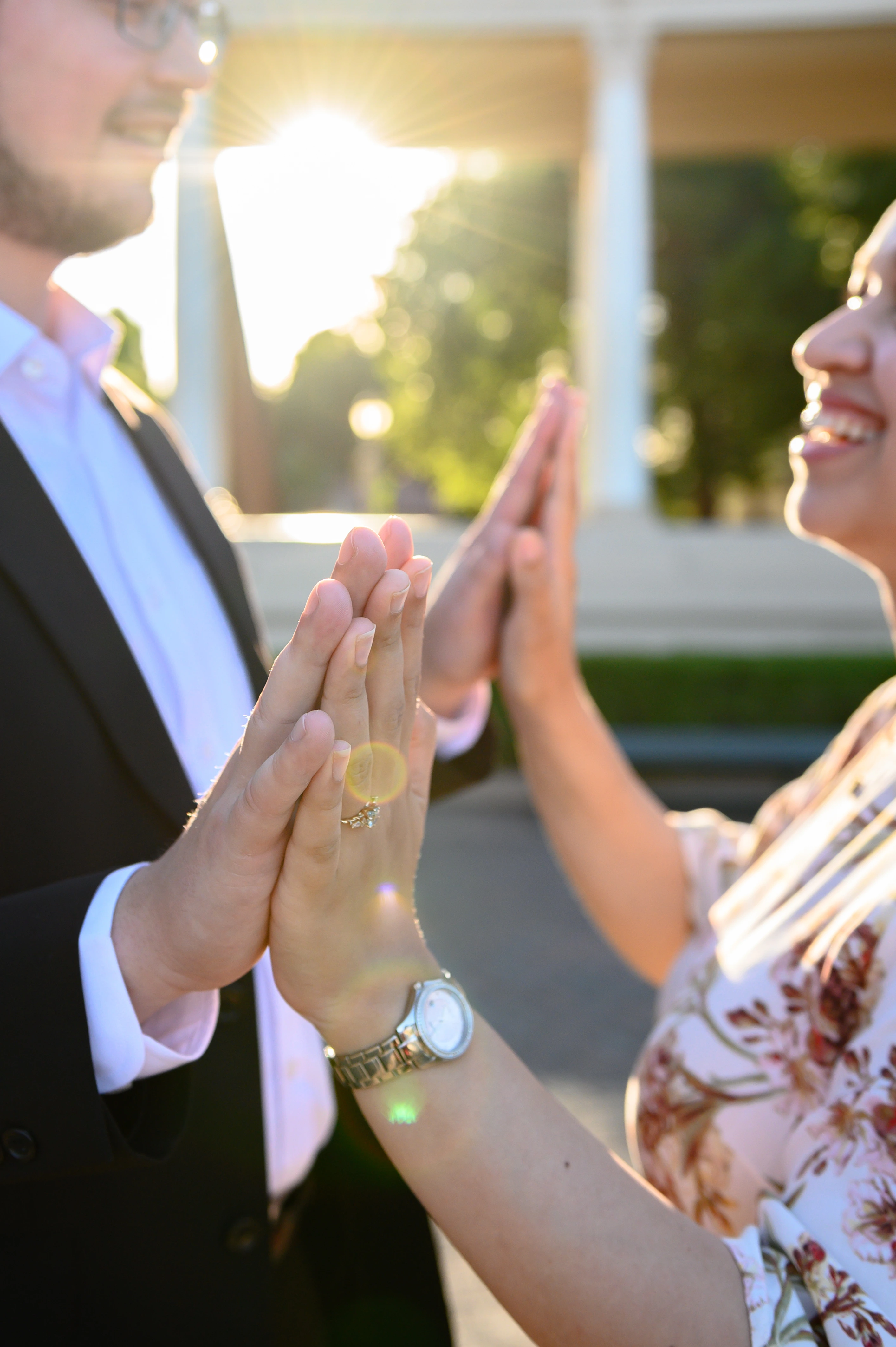 Two hands are pressed together in a playful gesture, illuminated by the warm glow of sunlight in a joyful outdoor atmosphere
