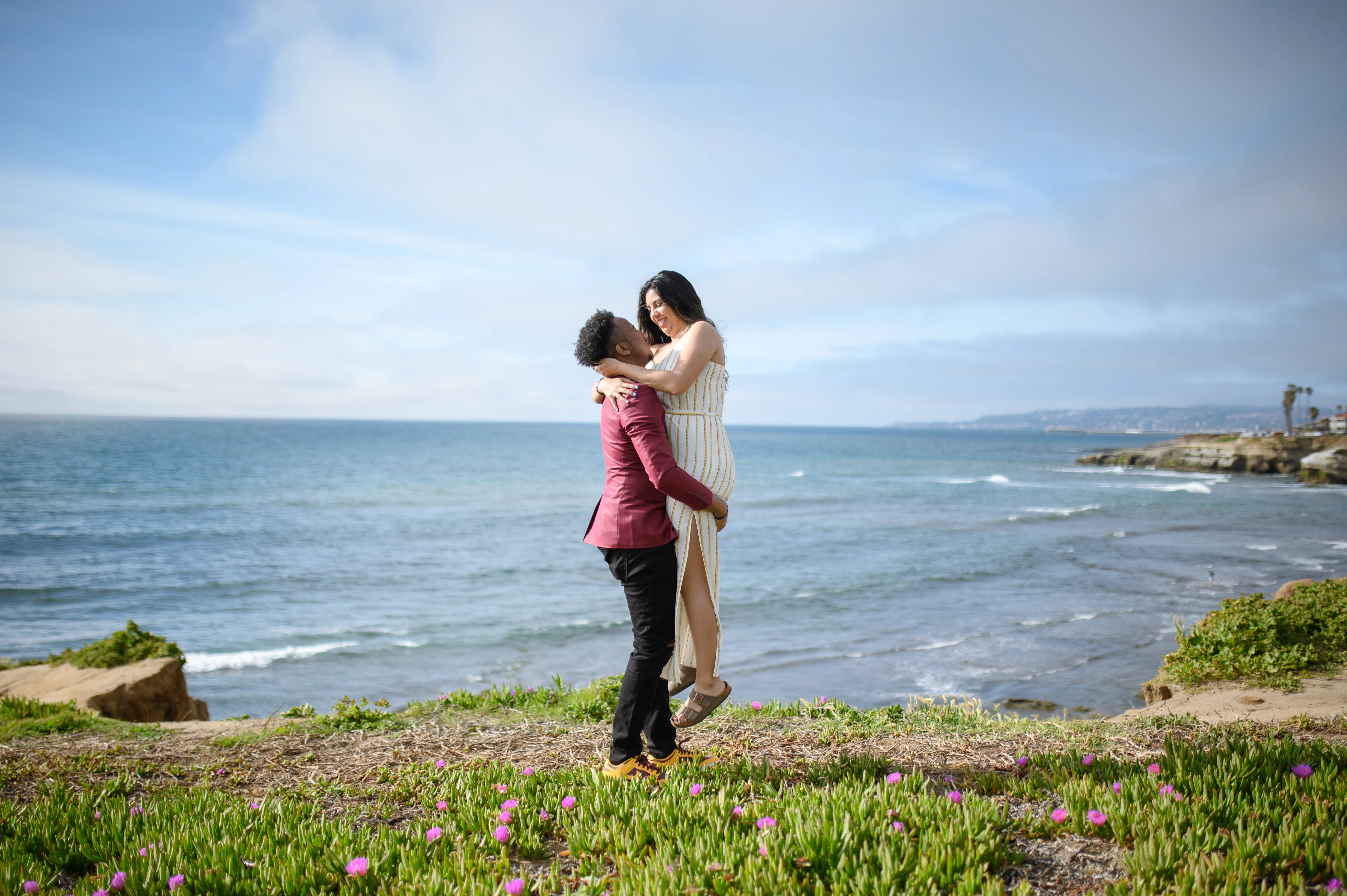 A romantic proposal photographer in San Diego captures a couple celebrating their engagement at Sunset Cliffs, showcasing the beauty of love and the ocean backdrop.