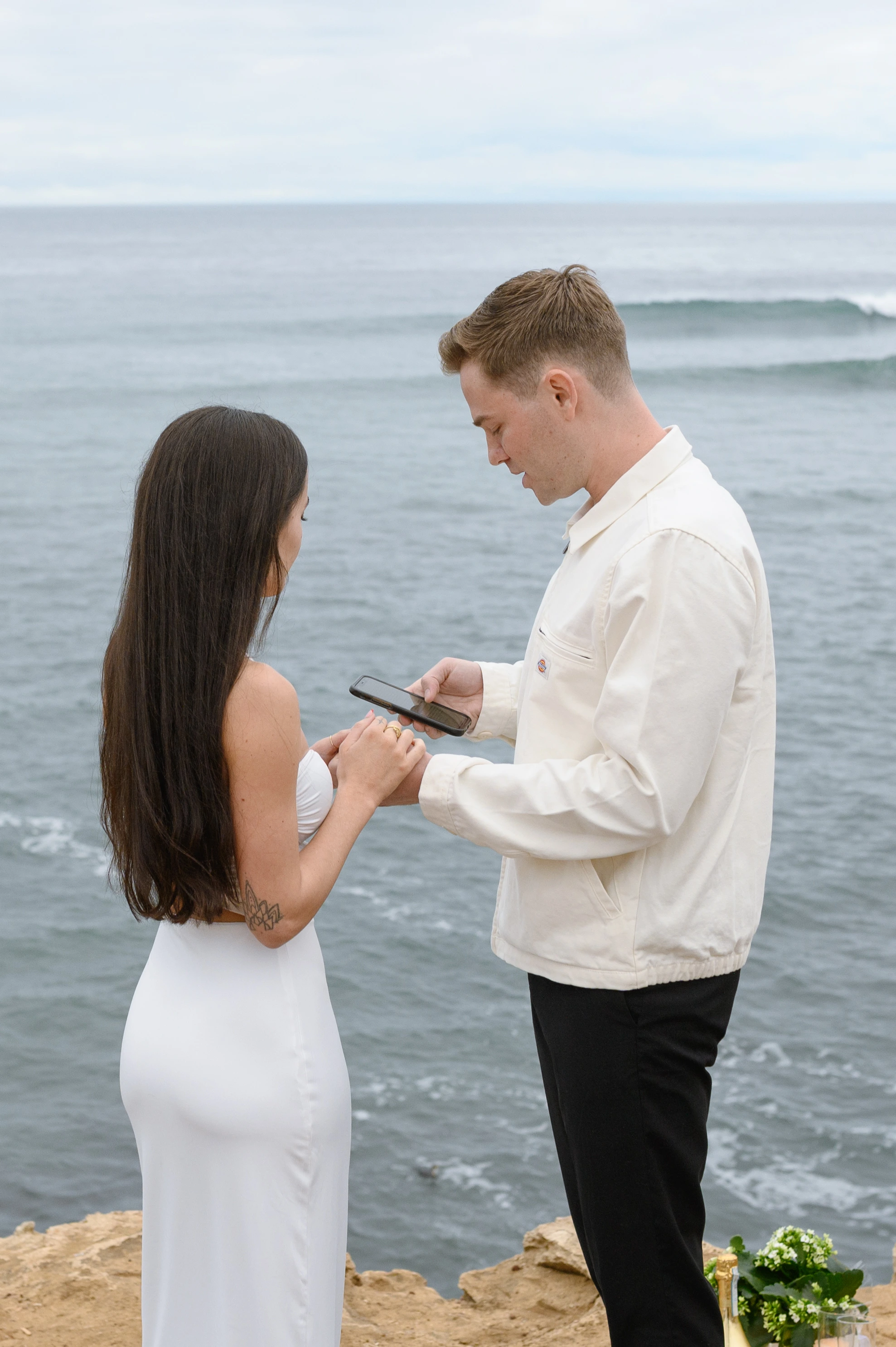 man reading proposal speech from phone Sunset Cliffs