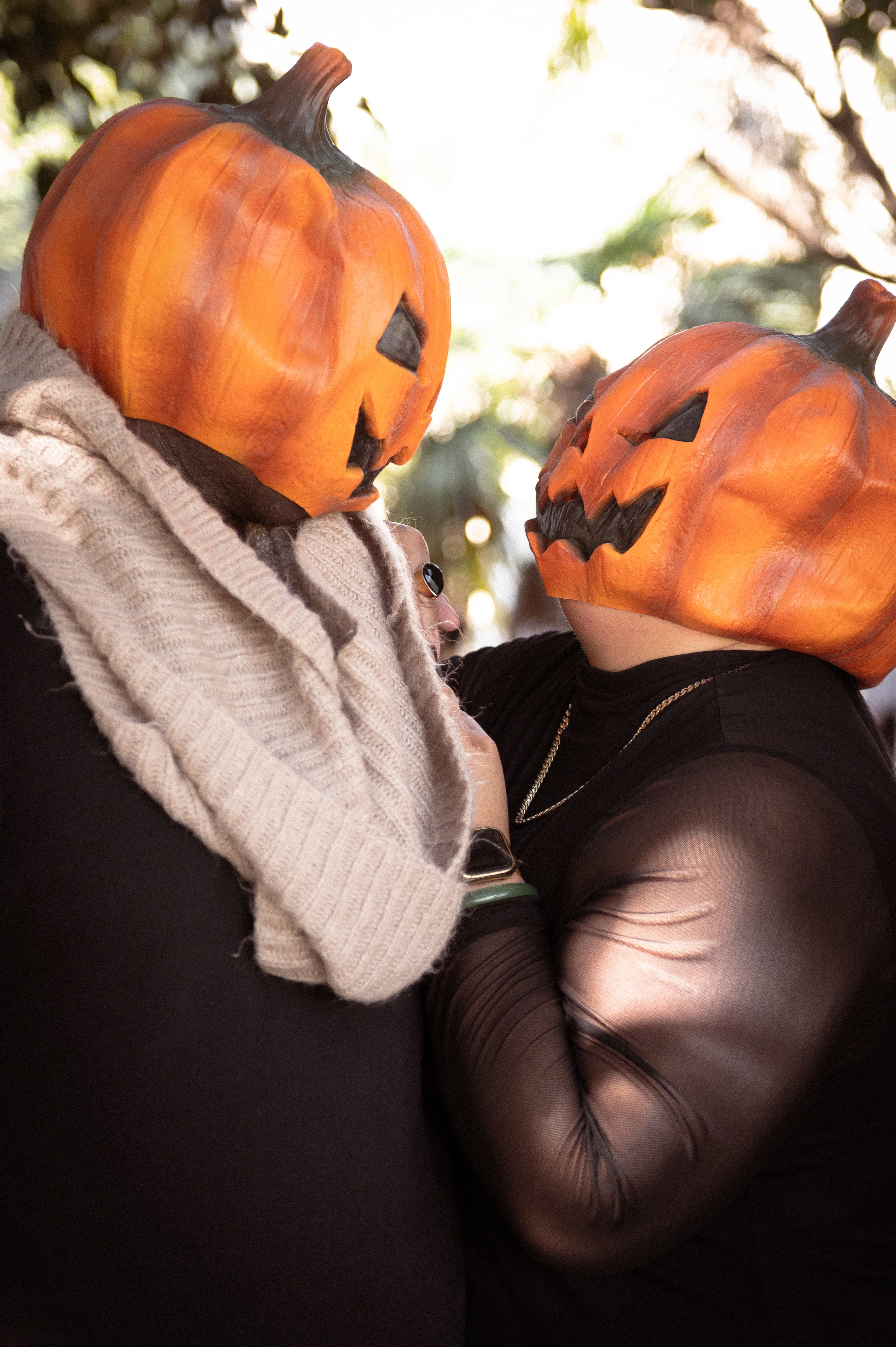 Capturing the essence of love and Halloween spirit, this couple's photoshoot in San Diego features a cozy embrace, showcasing their playful pumpkin masks and connection.