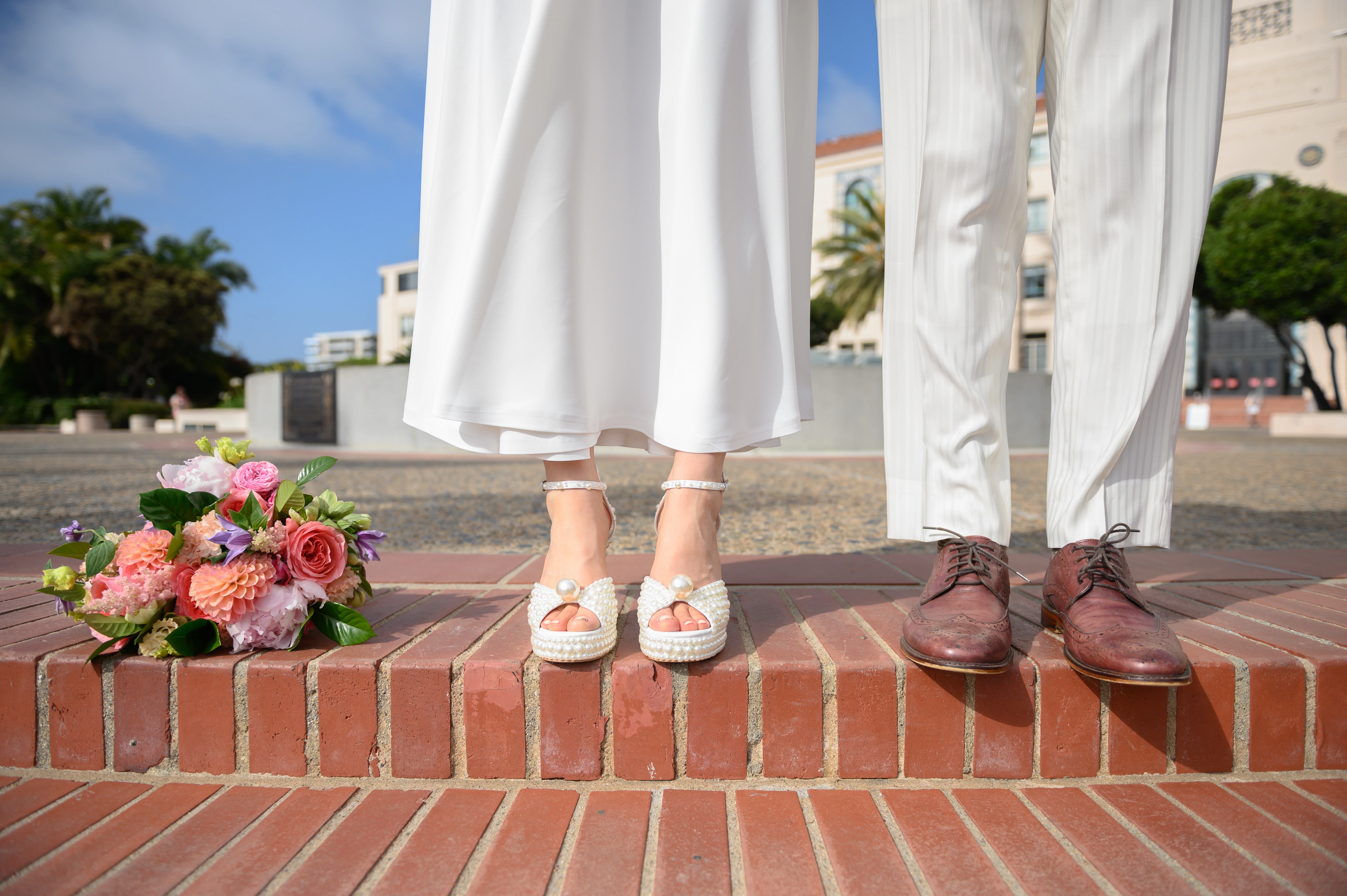 Close-up of the couple’s shoes and a bridal bouquet resting on brick stairs, highlighting textures and wedding details