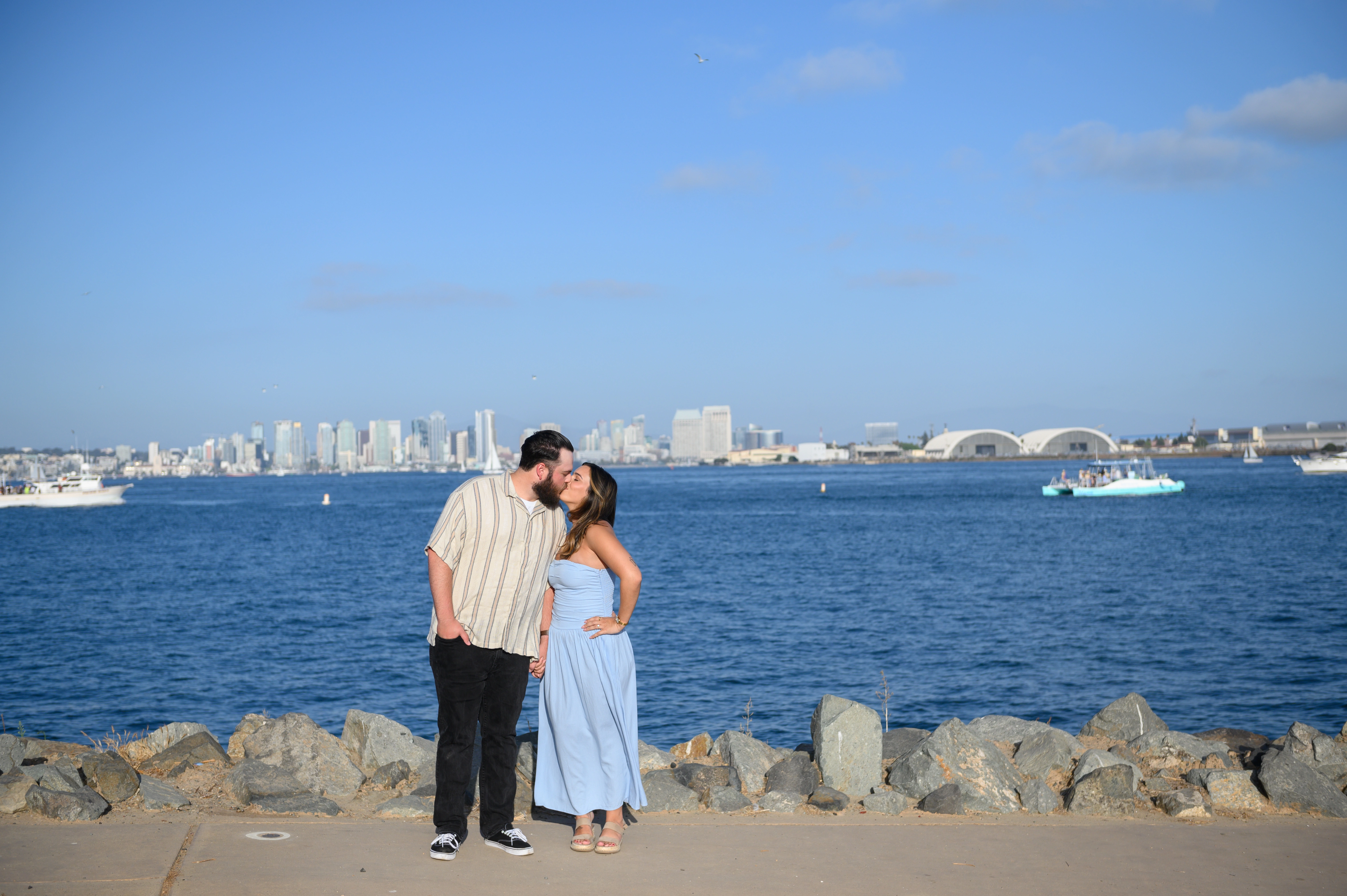 Romantic couple kissing at the San Diego waterfront, showcasing the beautiful skyline, perfect for a San Diego proposal photographer.