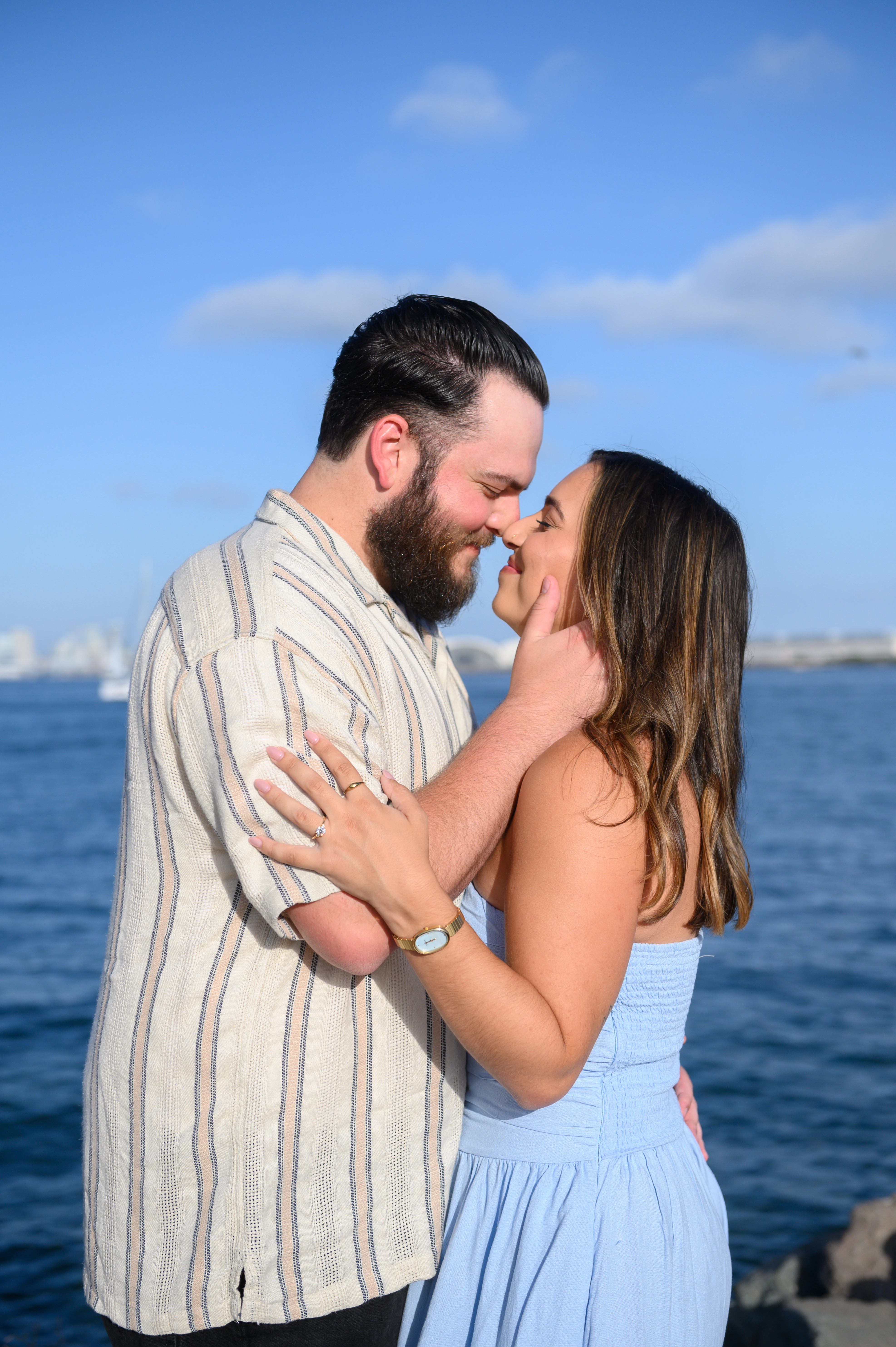 San Diego proposal photographer captures a couple sharing a kiss by the water, highlighting the romantic atmosphere of their engagement in San Diego.