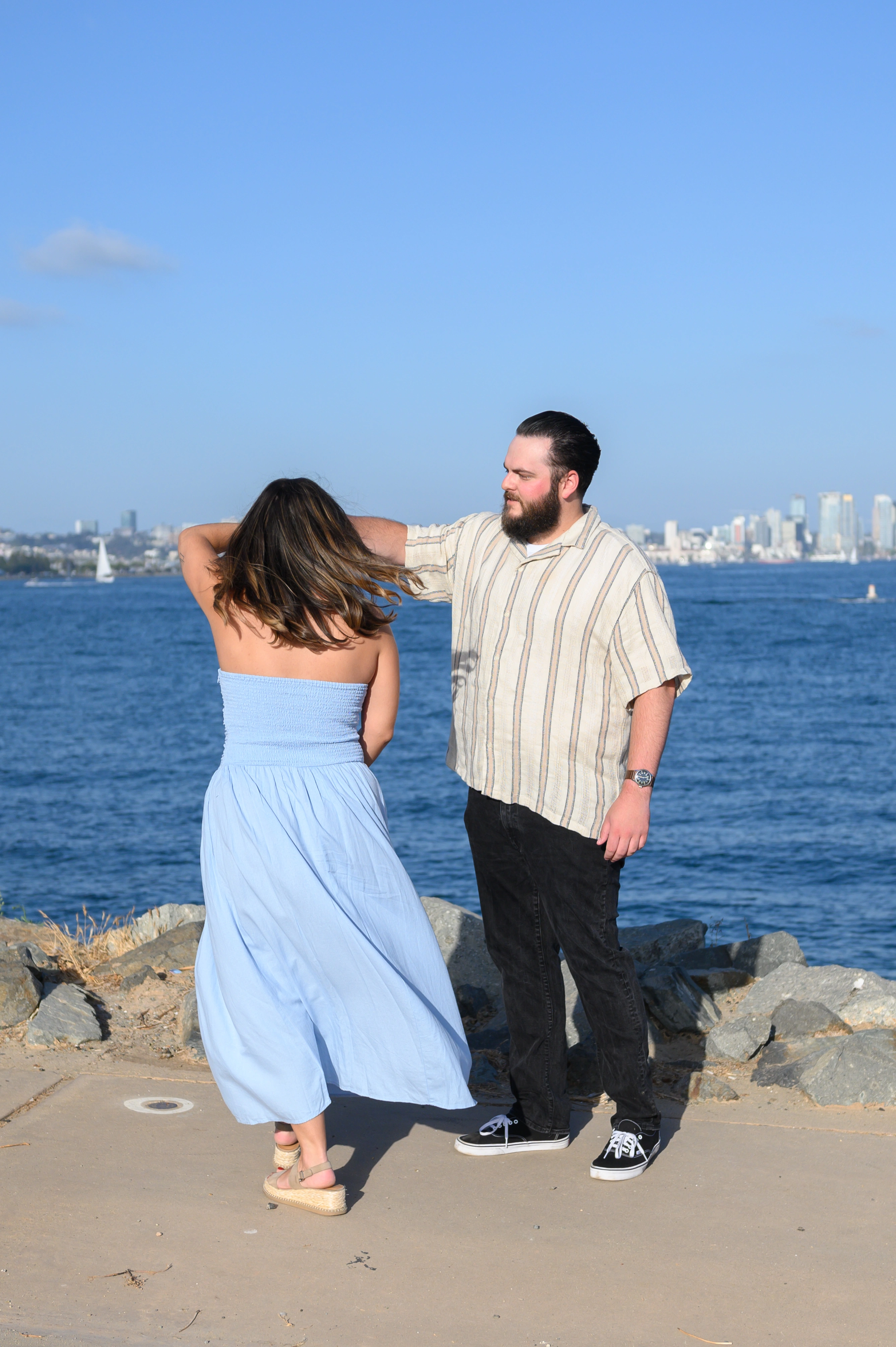 A couple dancing joyfully at the San Diego waterfront after a proposal, with the city skyline in the background. This image represents the essence of a romantic proposal photographer in San Diego, perfect for couples looking for the best engagement photography experience.