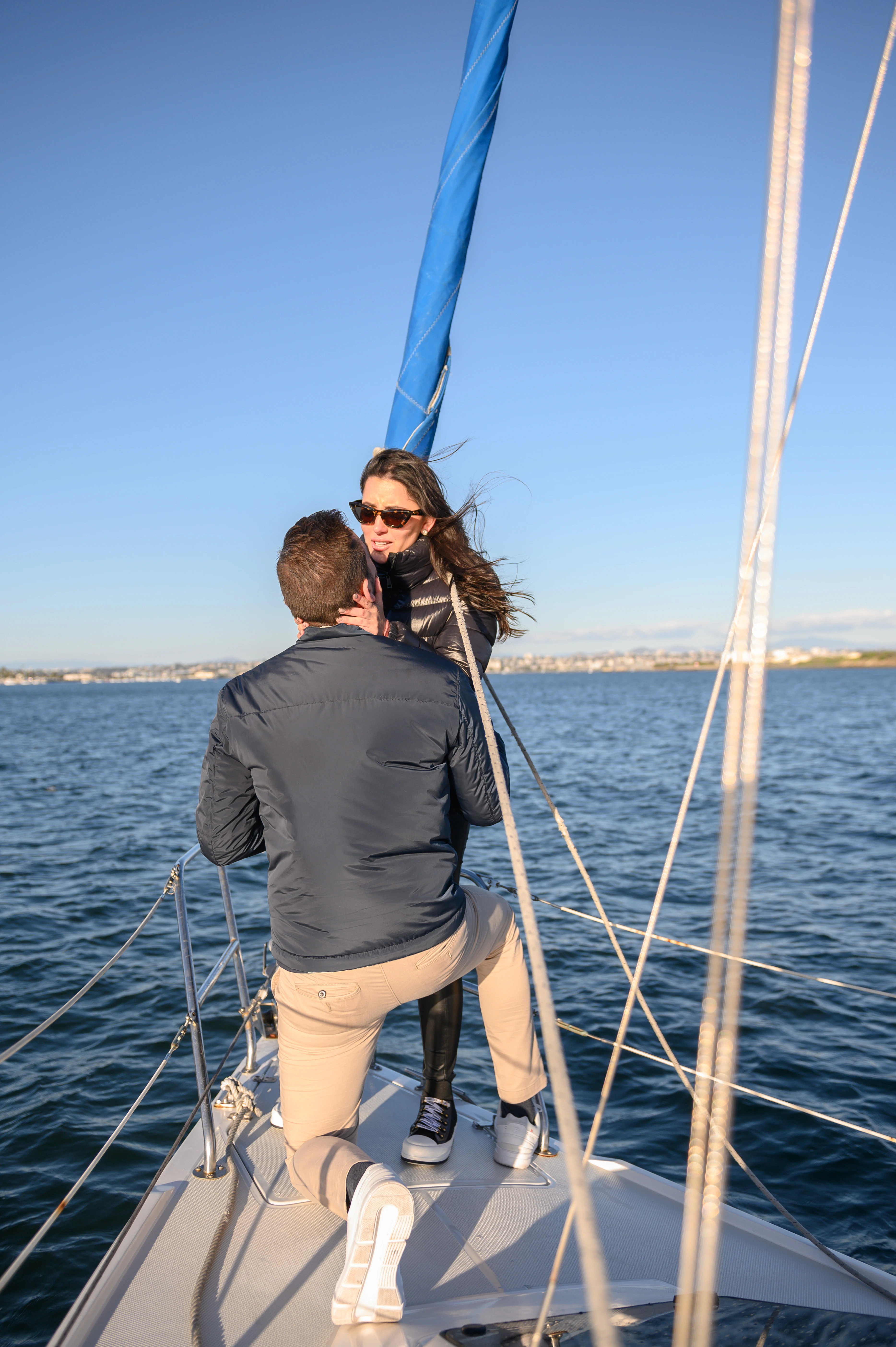Sailboat proposal in San Diego, highlighting a couple's intimate moment against the backdrop of the ocean and city skyline.