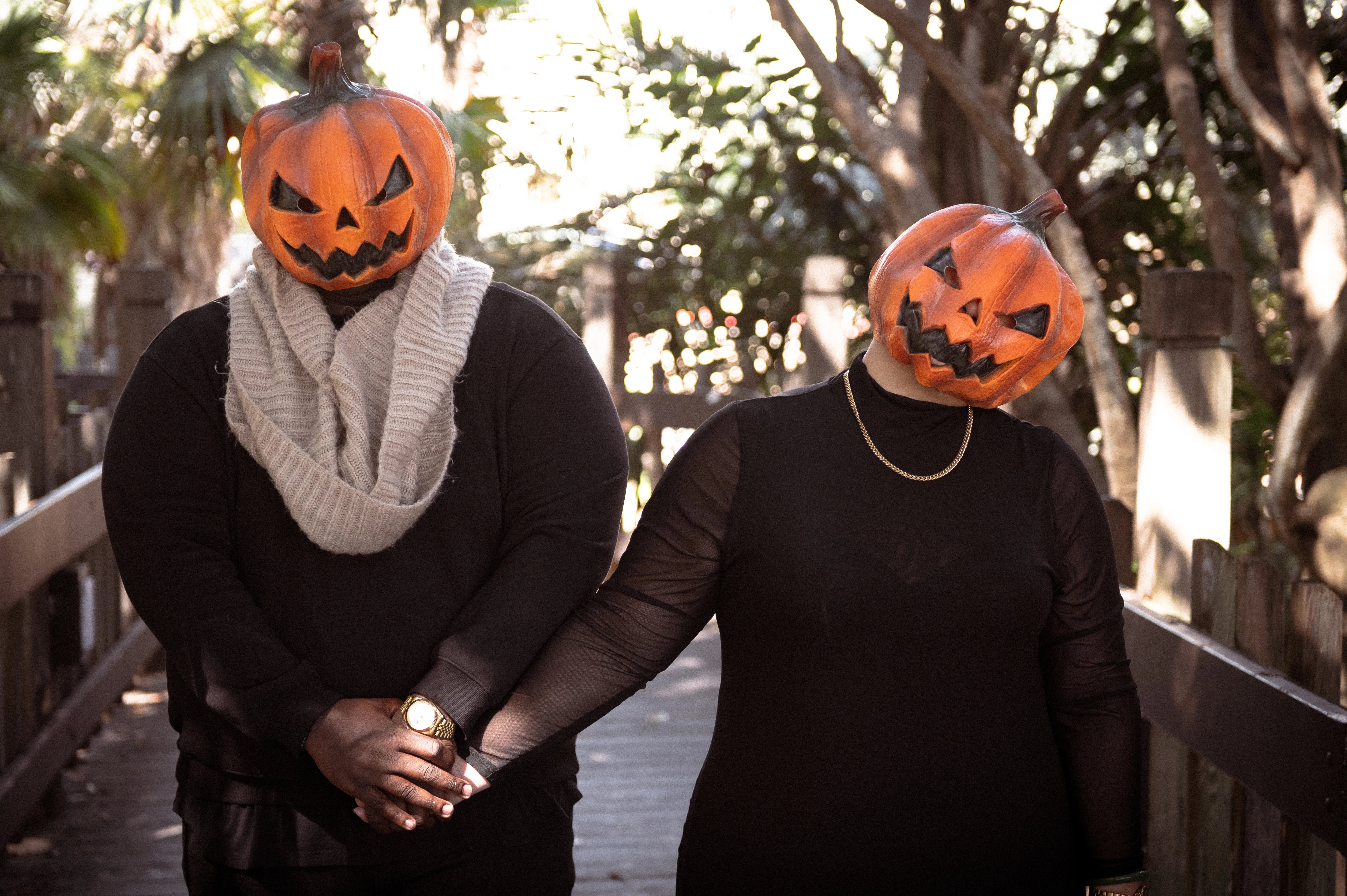 This Halloween couples photoshoot in San Diego highlights the couple's spooky style, as they stroll hand-in-hand on a scenic wooden bridge, embodying romance and fun.