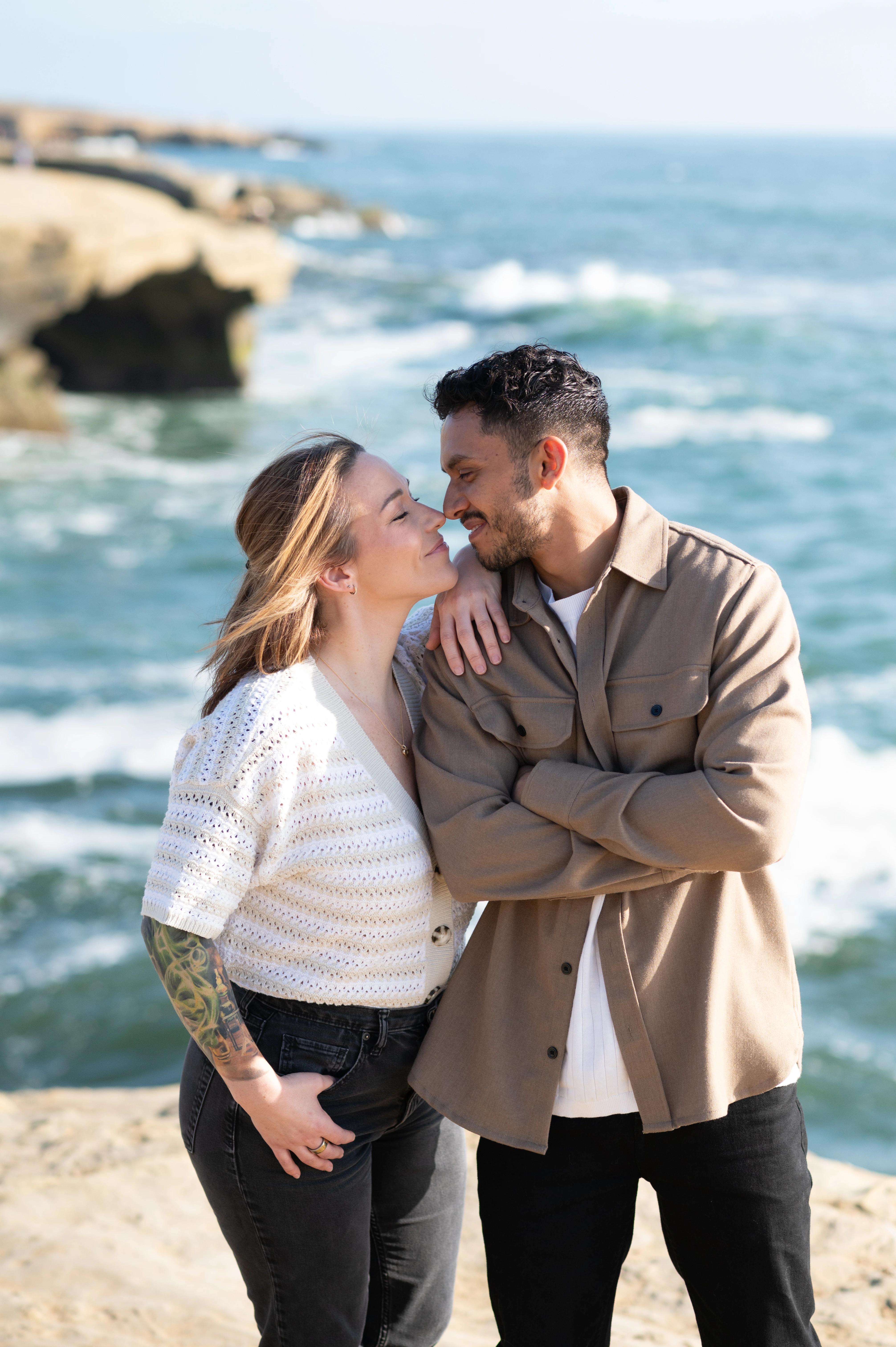 An intimate moment captured during an engagement session at Sunset Cliffs, San Diego. The couple shares a tender kiss, framed by the stunning ocean backdrop. This photograph beautifully showcases the love and connection between them, perfect for couples seeking to celebrate their engagement or marriage proposal.