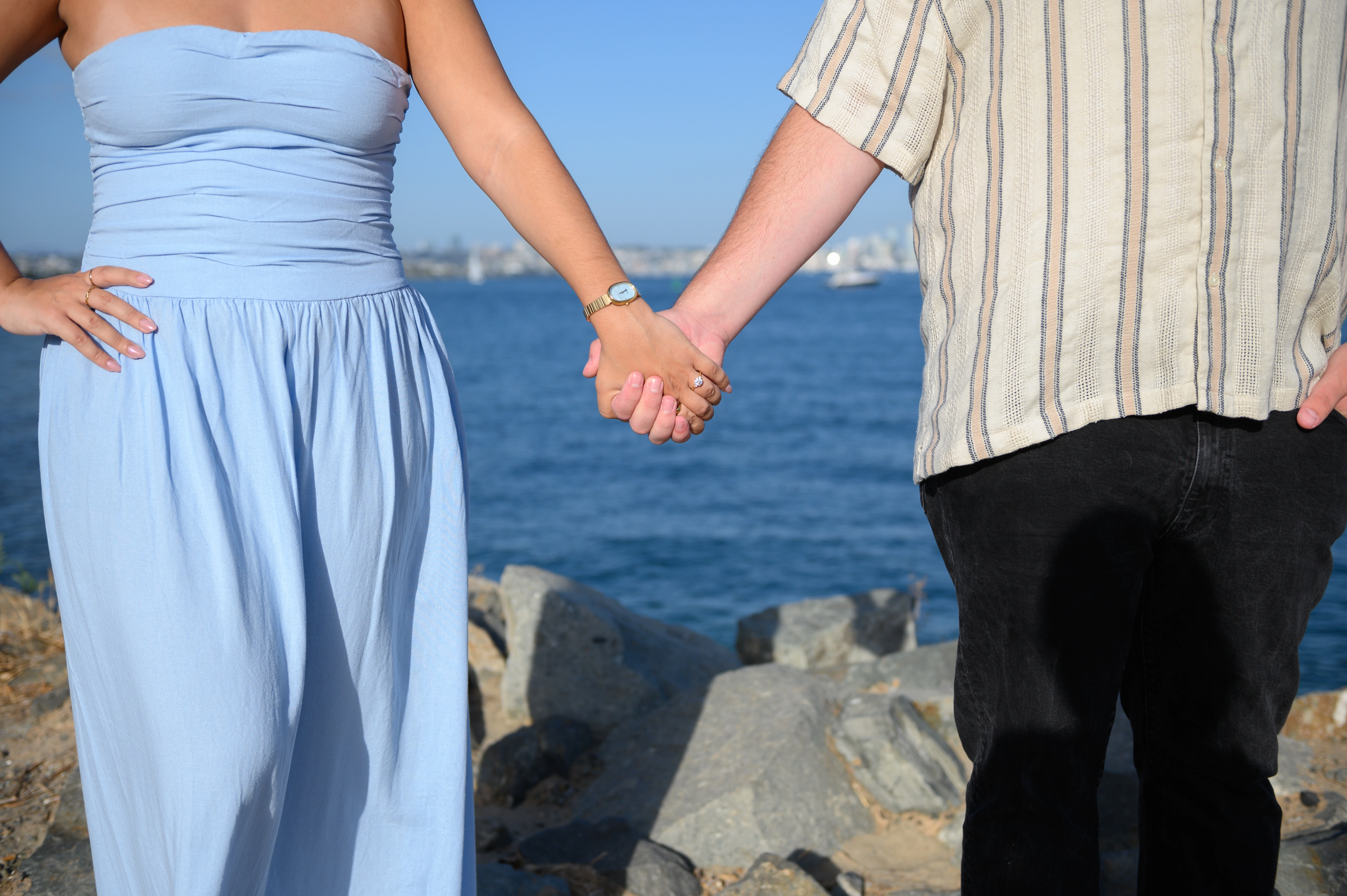 A close-up shot of a couple's hands intertwined at the San Diego waterfront, emphasizing the intimacy of their engagement. This image is ideal for those searching for an affordable San Diego proposal photographer who captures genuine moments.