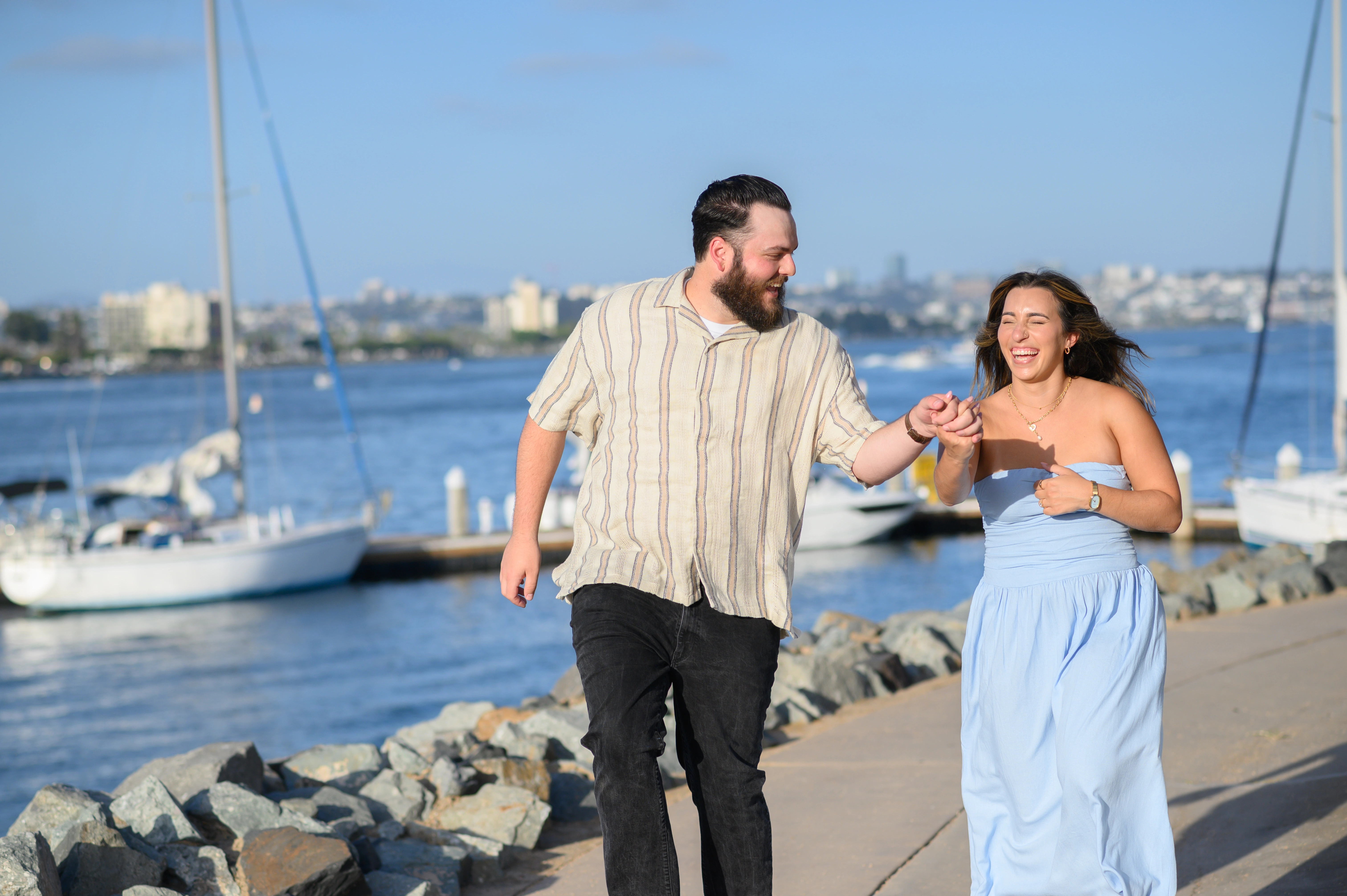 Couple walking together by the San Diego waterfront, showcasing the beauty of San Diego engagement photography.