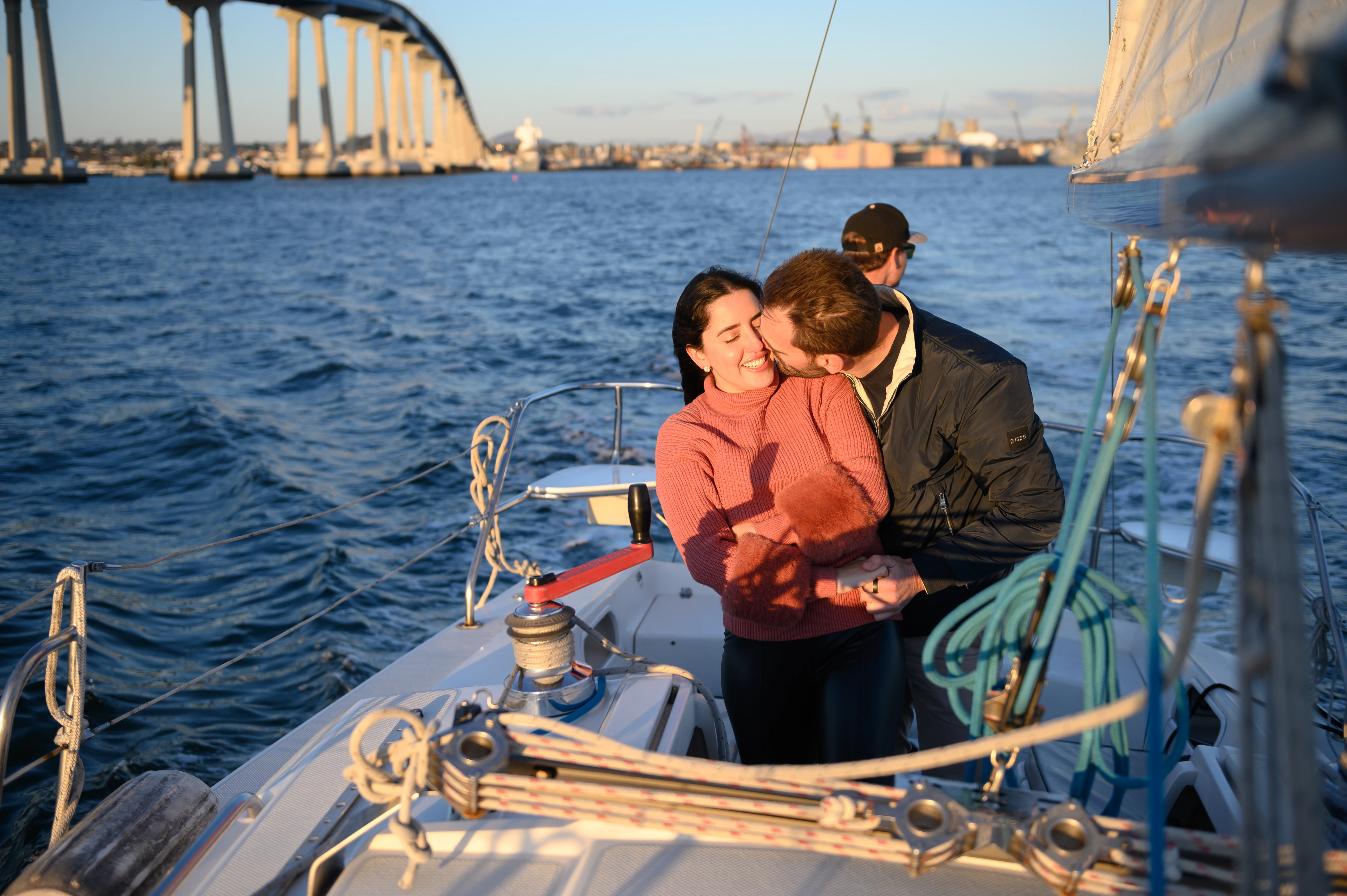 Couple sharing a kiss on a sailboat in San Diego after a romantic engagement proposal, highlighting the scenic beauty. Affordable San Diego proposal photographer.