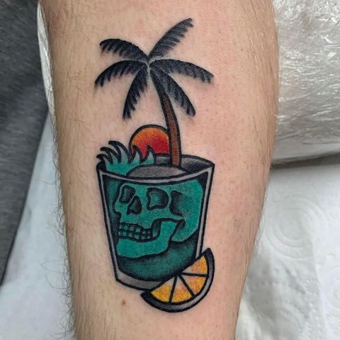 old school trad tattoo of a skull in a cocktail glass, with waves, lemon and palm tree by Will at Paradise tattoo High Wycombe  