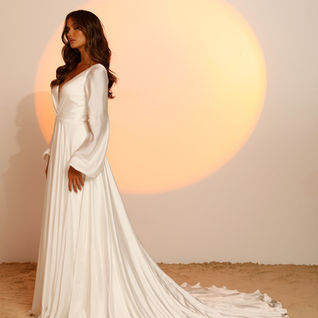 A line wedding dress. V neck, plunging back. Ivory, pleated bodice. Sleeves. Madi Lane.