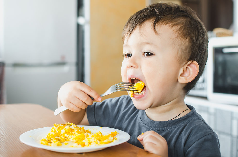 Baby eating scrambled eggs, introducing common allergenic foods early.